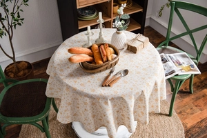 Detail of round cotton linen tablecloth with gold Christmas bells and snowflake prints