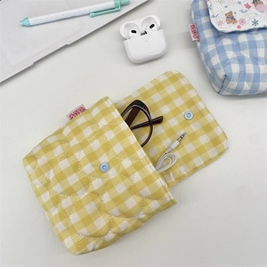 Close-up of the yellow gingham quilted storage pouch holding glasses and earphones