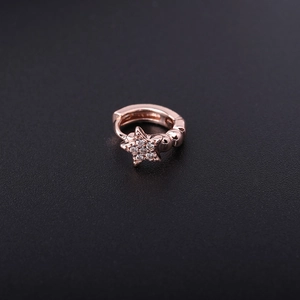 Rose gold huggie earring with sparkling cubic zirconia star pendant on a dark background