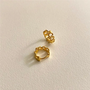 Detail showing high-polish gold chain link hoop earrings on a textured background