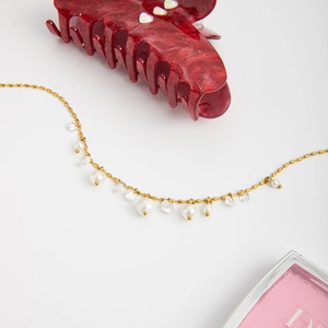 Detailed view of 18K gold stainless steel chain with white pearls and sparkling crystals