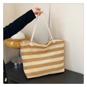 Detail of hand-woven striped straw tote bag with sturdy white rope handles and texture