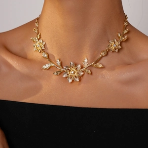 Close-up of golden floral leaf necklace with small crystals on a female model neck