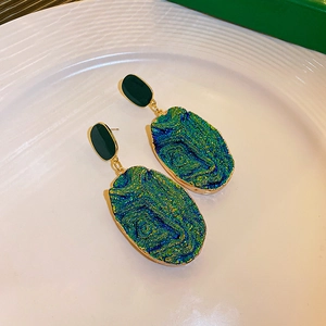 Macro shot of blue textured resin drop earrings with vintage gold metal edges in a dish