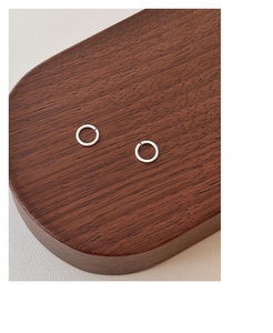 Close-up of minimalist S999 sterling silver hoop earrings on a dark wood display tray