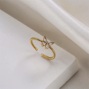 Macro shot of gold adjustable butterfly ring with sparkling zircons on soft fabric