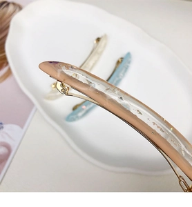 Dettaglio macro della clip per capelli in resina rosa con scaglie di lamina d'argento