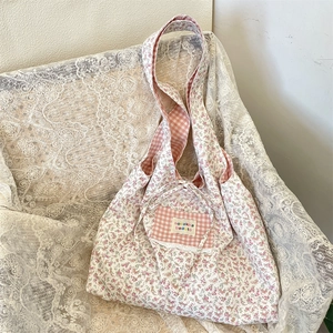 Close-up of floral canvas tote bag featuring a pink checkered pocket and tie closure