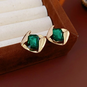Nahaufnahme von Vintage-Ohrringen mit smaragdgrünem Harz und goldenem Metallrand in Box