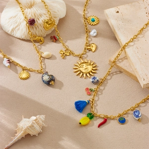 Detail of gold charms featuring shells, starfish and sun pendants on stainless necklaces