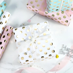 Rolls of pastel polka dot gift wrapping paper with metallic gold foil accents for birthdays