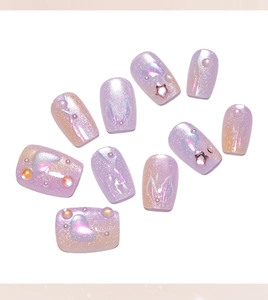 Detail of purple cat eye press-on nails with 3D pearls and star glitter accents