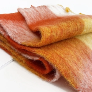 Close-up of fluffy mohair scarf with soft orange and coral pink gradient plaid texture