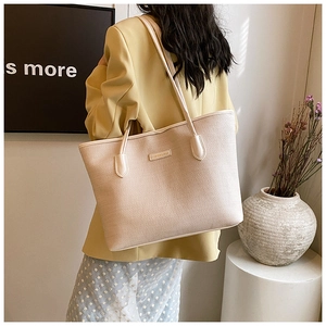 Detail of beige woven tote bag showing the fine texture and fashion metal logo tag