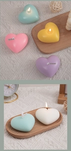 Detailed view of heart-shaped scented candles in pastel colors on a rustic wooden tray