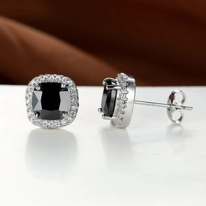 Detail shot of cushion-cut black gemstone stud earrings with white diamond halo