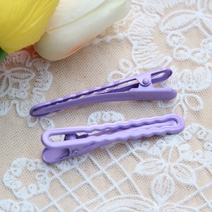 Close-up of two purple electroplated metal hair clips with smooth and wavy textures