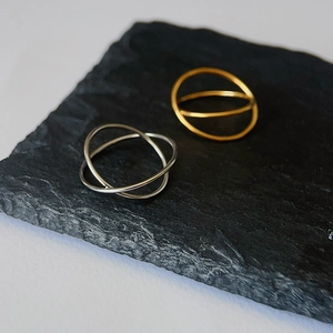 Detailed view of interlocking gold and silver titanium steel rings on dark stone surface