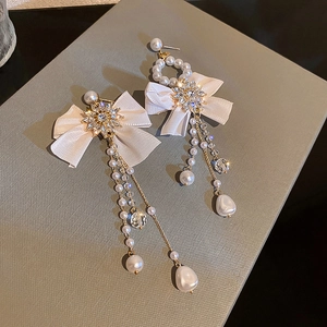 Macro detail of asymmetric bow earrings with pearls and rhinestones on velvet box