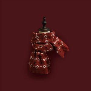 Close-up of a red knitted Christmas scarf with detailed white and black snowflake patterns