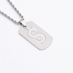 Gros plan d'un collier en acier inoxydable argenté avec un pendentif évidé en forme de S