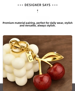 Detail of red glitter cherry keychain with golden metal clasp and letter C tag