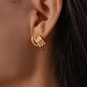 Close-up of triple-layered gold geometric C-shaped earrings worn by a model