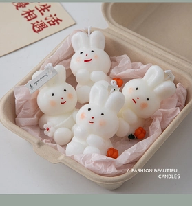 Top view of four cute rabbit scented candles in a gift box with pink tissue paper