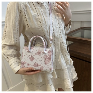 Dettaglio della piccola borsa tote beige con stampe di farfalle e tracolla rimovibile