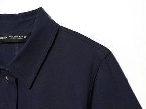 Gros plan du col d'une robe chemise en sergé bleu marine avec étiquette et texture du tissu