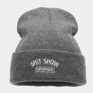 Dettaglio del ricamo SHIT SHOW su un berretto in maglia di acrilico grigio scuro
