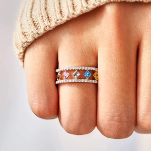 Macro-opname van een kleurrijke edelsteenring met pavé-diamanten bij een gebreide mouw