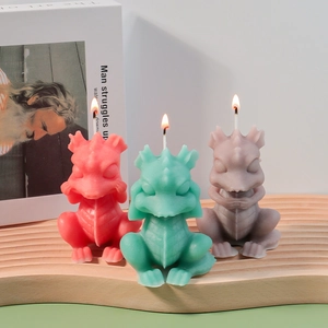 Three dragon-shaped scented candles in red, cyan and gray on a wooden tray