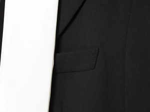 Détails de la texture du blazer noir avec coutures précises et finition de la poche