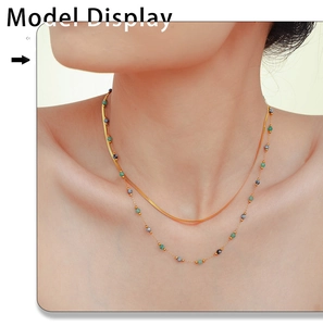 Detailed view of a double-layer gold snake chain necklace with green stone bead accents