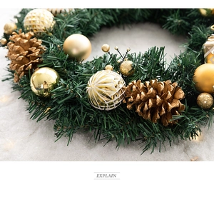 Close-up of artificial Christmas wreath with golden ornaments and pine cones on snow