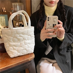 Quilted white petal style handbag on a wooden counter for daily snack storage