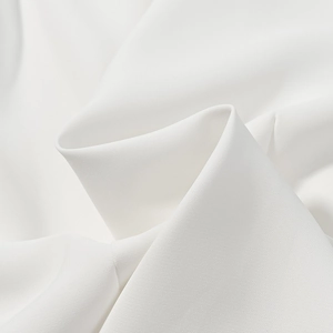Gros plan du tissu blanc montrant le tissage fin et le drapé fluide de cet ensemble chic