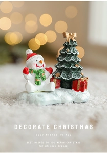 Detail view of snowman with Christmas tree and red gift bag on a snowy ground