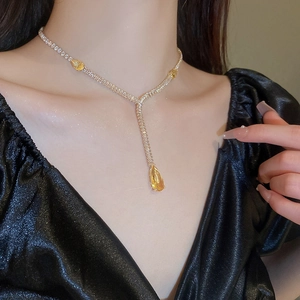 Détail d'un collier doré orné de diamants et d'un cristal jaune en forme de poire éclatant