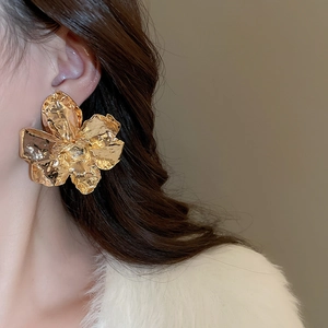 Close-up of golden textured flower earring featuring layered metallic pleated petals