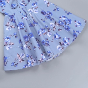 Detailansicht des hellblauen Blumenkleidsaums mit eleganten blauen Rosenmustern und Falten