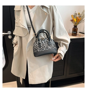 Fashionable leopard print shell bag shown with gold hardware and shoulder strap detail