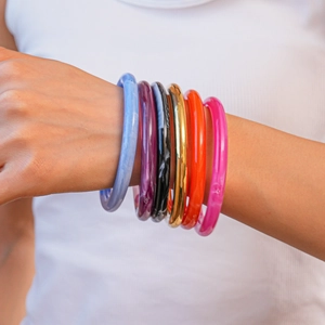 Gros plan de bracelets géométriques empilés en acrylique coloré aux finitions marbrées