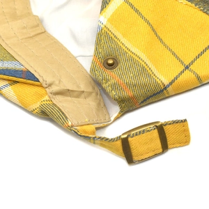 Detail of plaid newsboy cap showing yellow and blue check pattern and metal buckle