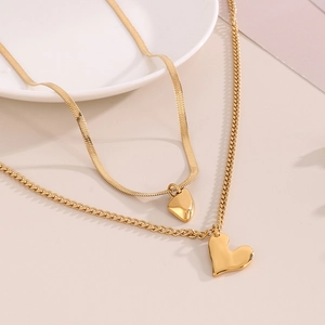 Detail of gold double-layer necklace with irregular heart pendant on snake and curb chains