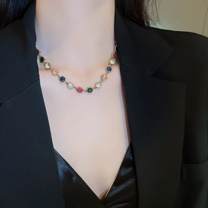 Detail of colorful round gemstone necklace with gold claw setting on model's neck