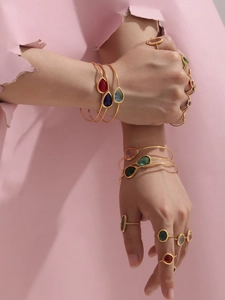 Close-up of gold stainless steel open bangles with colorful teardrop-shaped glass stones