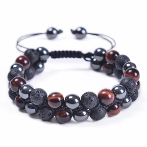 Macro detail of hand-woven bracelet with red tiger eye and porous black lava stone