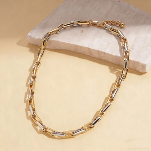 Detail shot of gold and silver two-tone chain link necklace on a textured stone